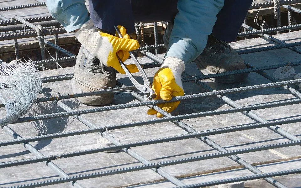 A worker ties together reinforcing bar, or rebar, to strengthen concrete floors for a facility that will house 372…